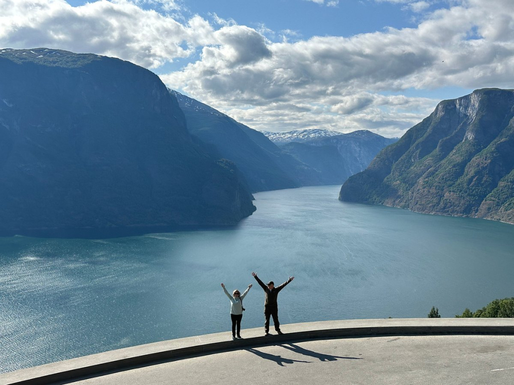 Panoramautsikt over den fabelaktige Hardangerfjorden med grønne fjelldaler og snødekte topper, tatt fra et utkikkspunkt på en privat tur med Jandis Fjord Tours.