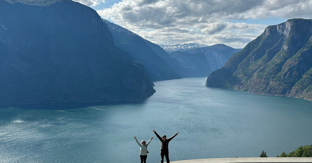 The iconic view that defines the Hardangerfjord Panoramautsikt over den fabelaktige Hardangerfjorden med grønne fjelldaler og snødekte topper, tatt fra et utkikkspunkt på en privat tur med Jandis Fjord Tours.